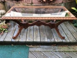 AN ITALIAN CARVED WALNUT GLASS TOPPED COFFEE TABLE