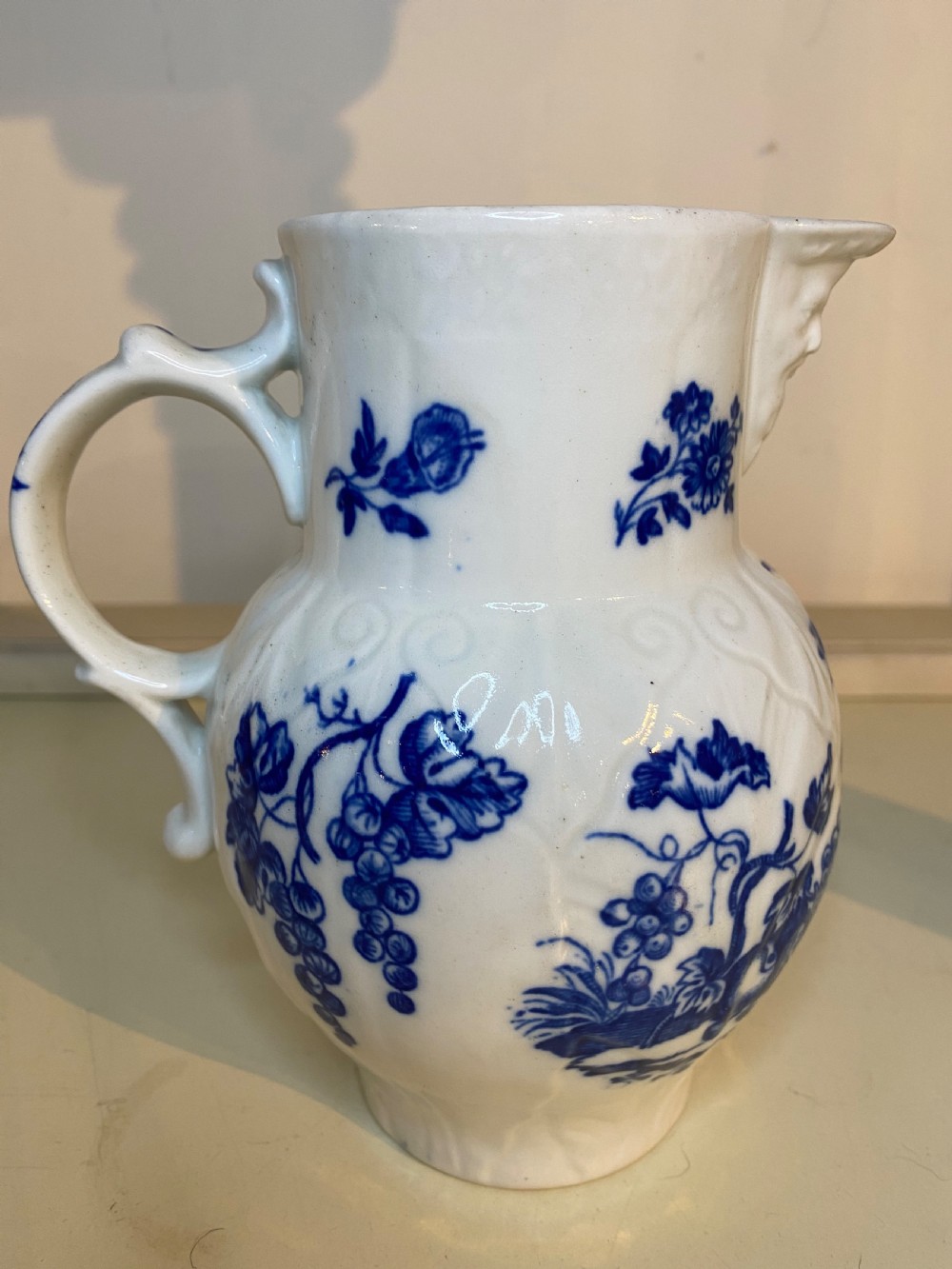 An antique Worcester blue and white porcelain jug featuring a moulded cabbage-leaf pattern, a bearded face mask spout, and bird decoration. View VII