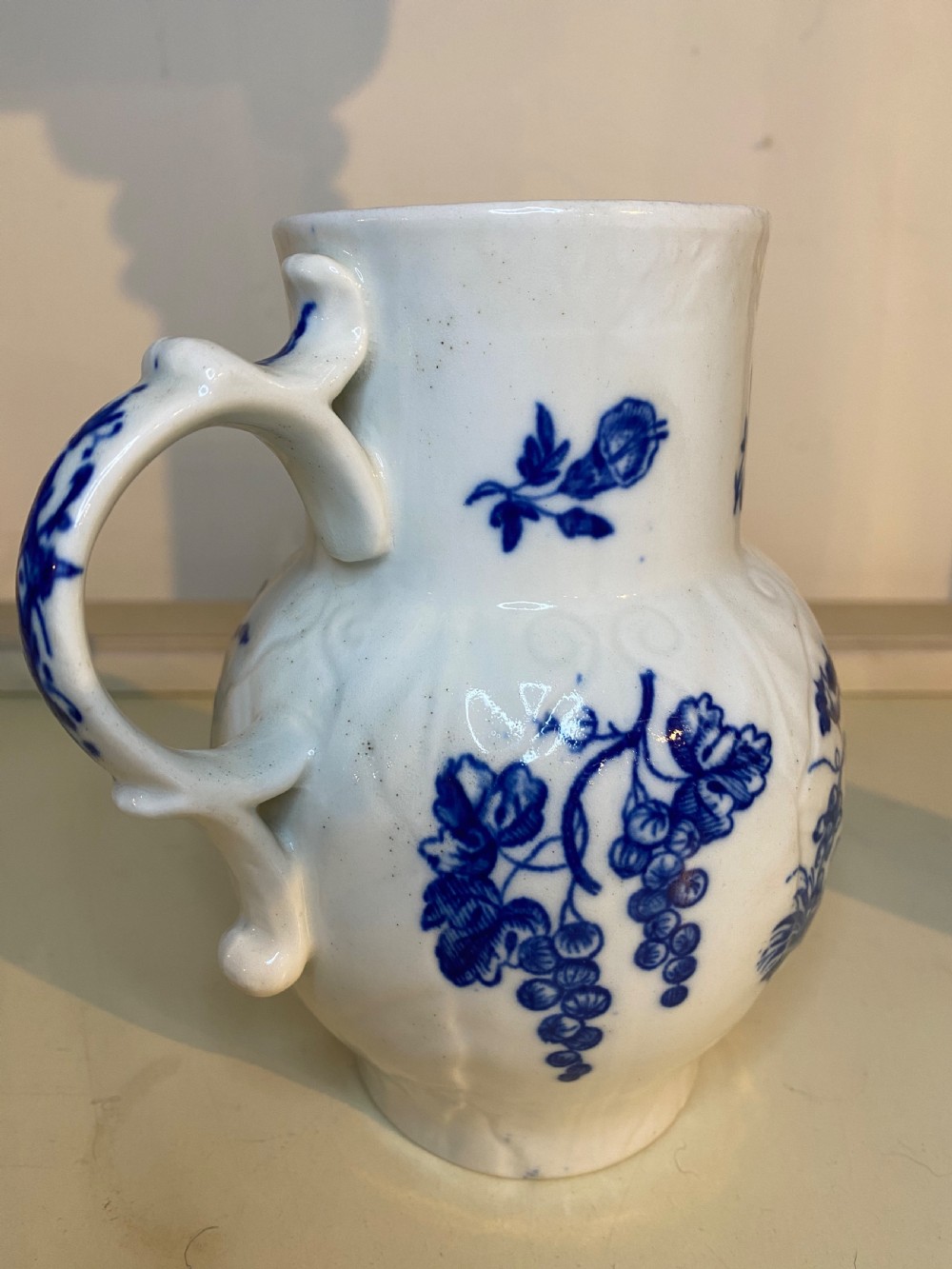 An antique Worcester blue and white porcelain jug featuring a moulded cabbage-leaf pattern, a bearded face mask spout, and bird decoration. View VIII