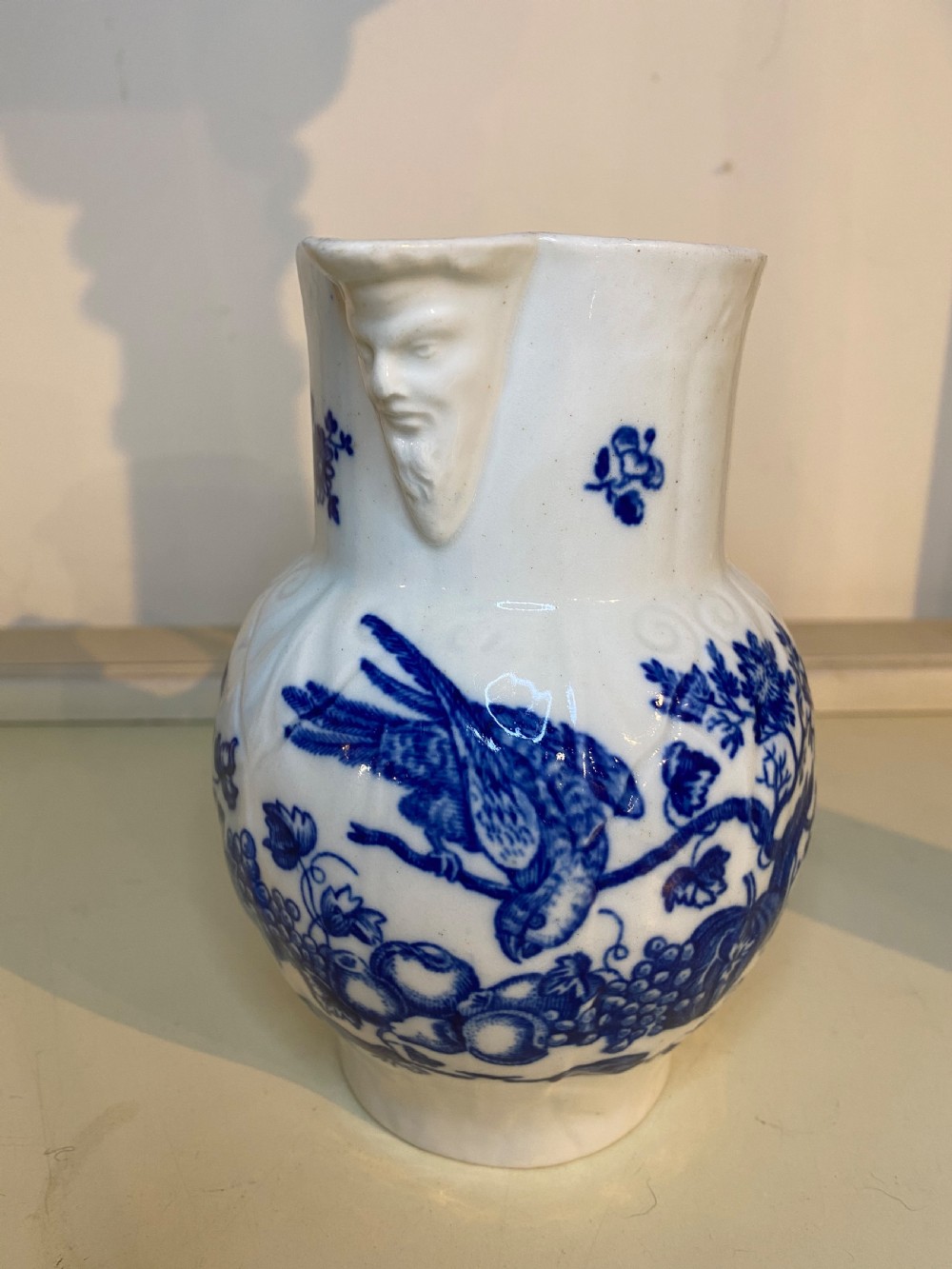An antique Worcester blue and white porcelain jug featuring a moulded cabbage-leaf pattern, a bearded face mask spout, and bird decoration. View XI