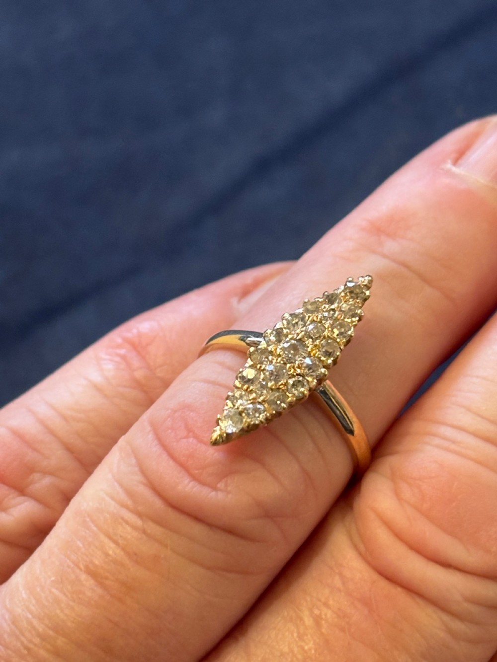 An antique 18ct yellow gold ring featuring an elongated marquise-shaped cluster set with multiple diamonds along a polished band. View VII