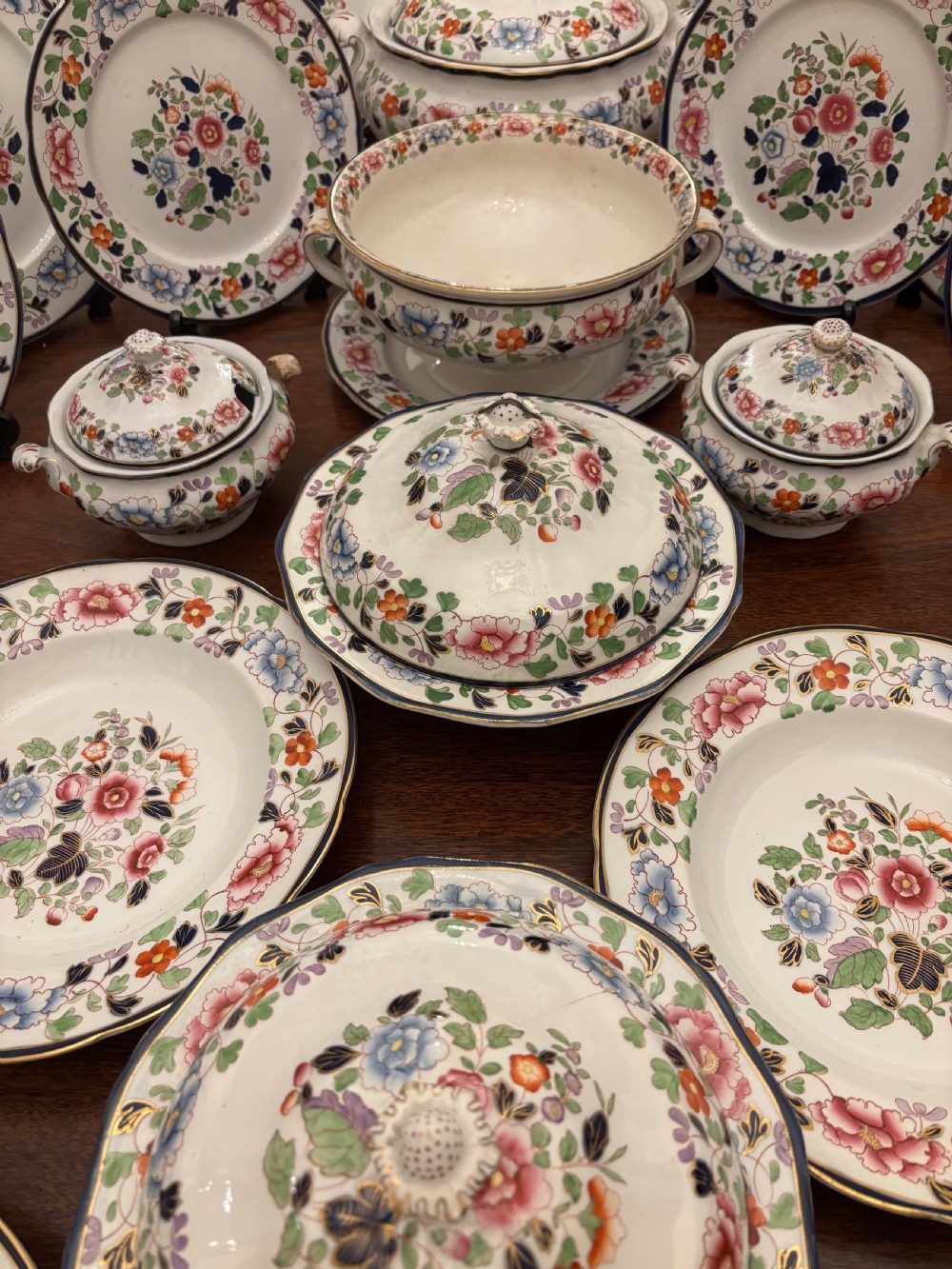 An extensive antique ceramic dinner service featuring floral transfers, matching tureens, bowls, and serving platters arranged together. View X