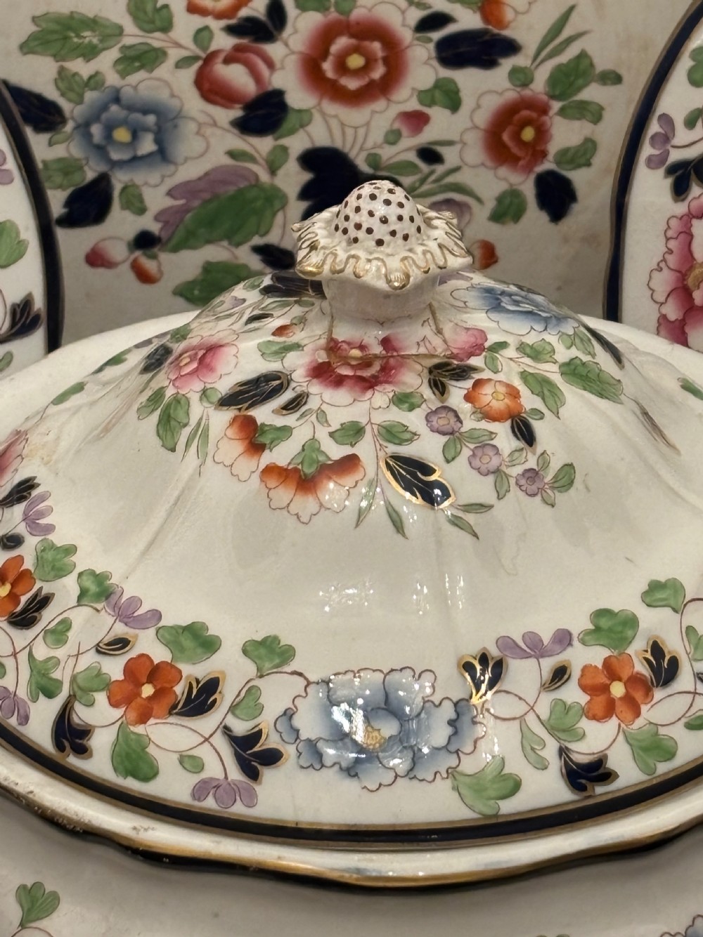 An extensive antique ceramic dinner service featuring floral transfers, matching tureens, bowls, and serving platters arranged together. View XI
