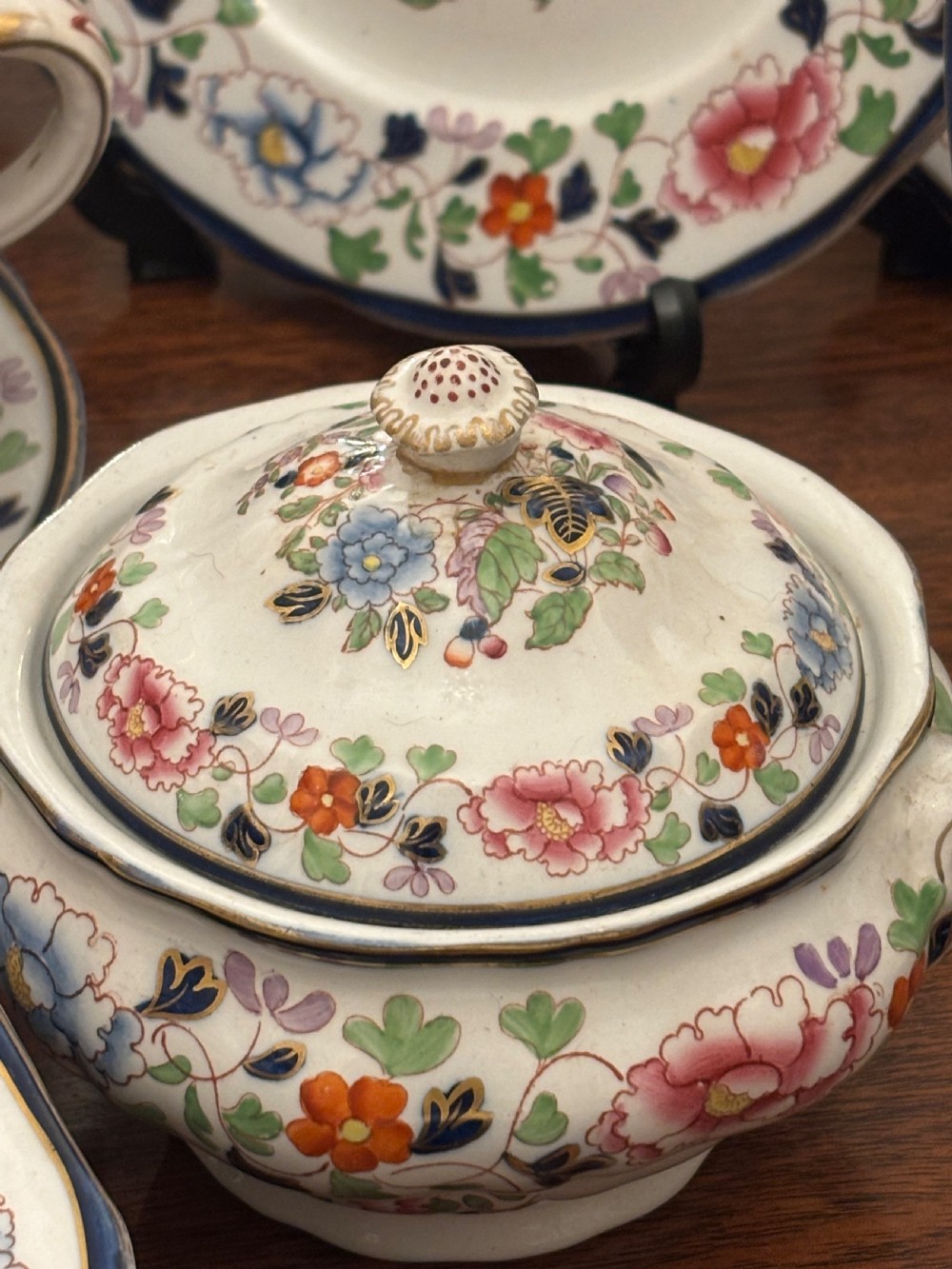 An extensive antique ceramic dinner service featuring floral transfers, matching tureens, bowls, and serving platters arranged together. View XII