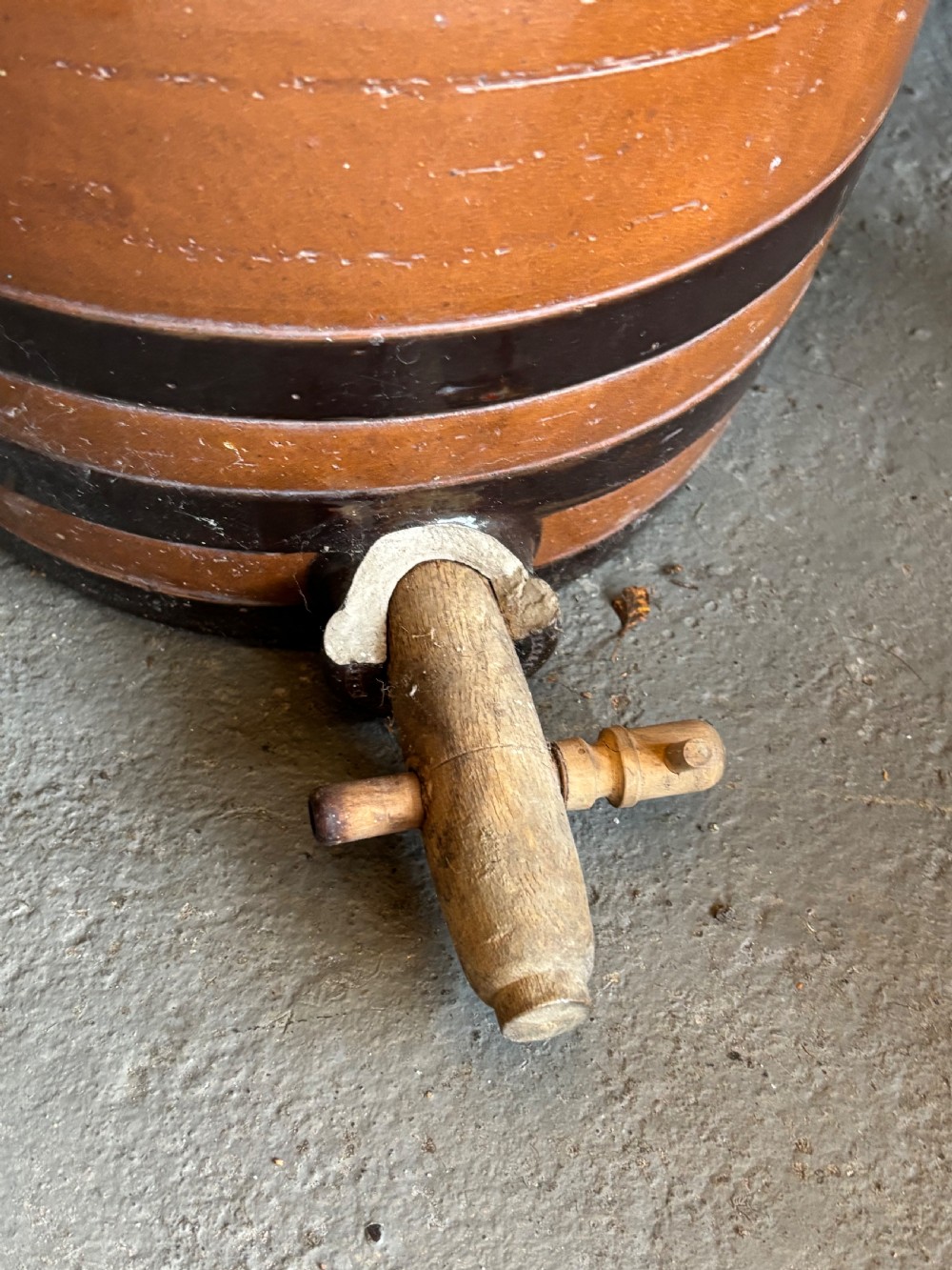 A Victorian Doulton Lambeth salt-glazed stoneware spirit cask featuring dark brown painted bands, a fitted wooden lid, and a wooden spigot tap at the base. View II