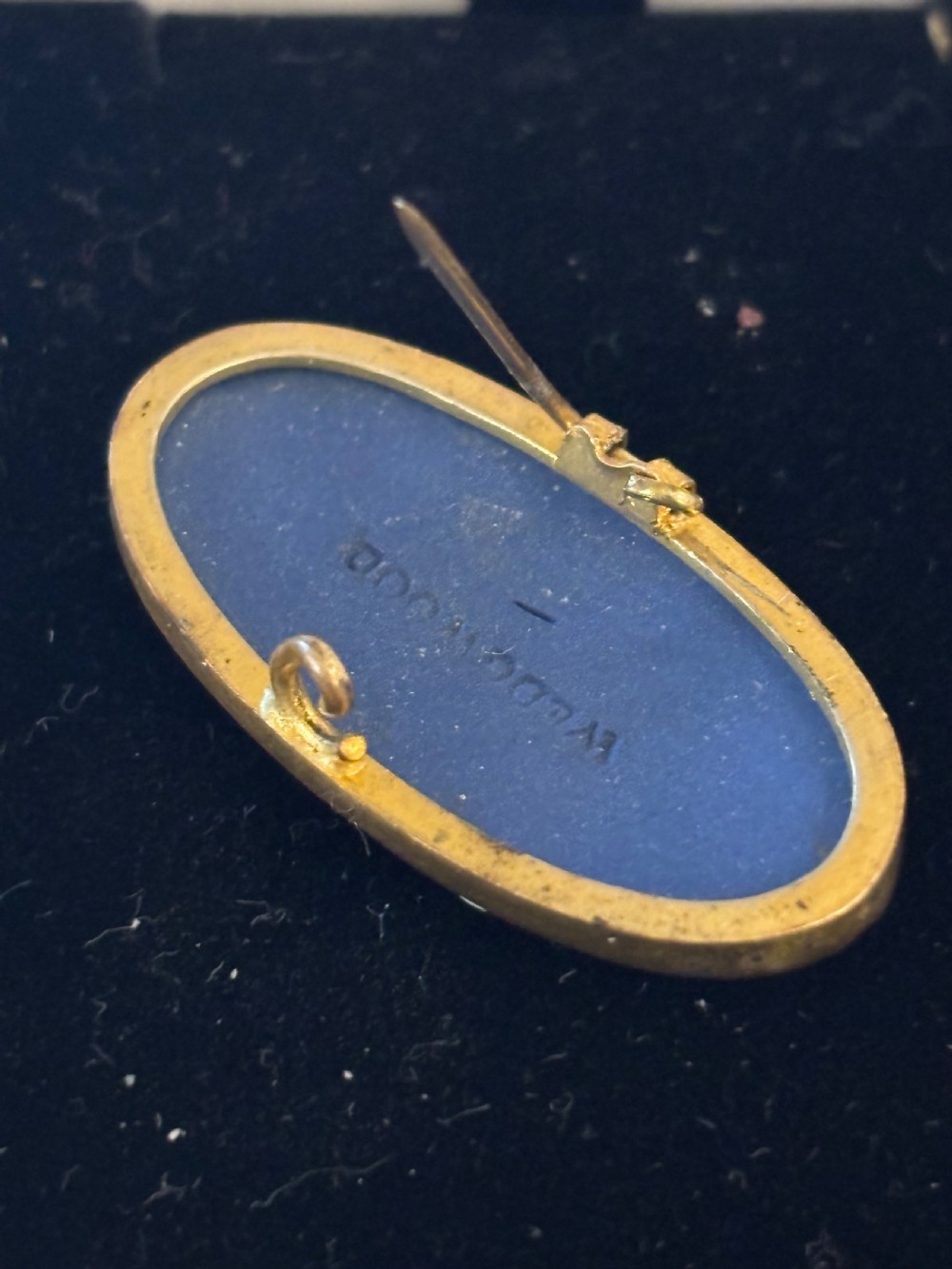 An oval blue jasperware brooch featuring a white bas-relief classical female figure with an anchor, mounted in a metal frame. View II