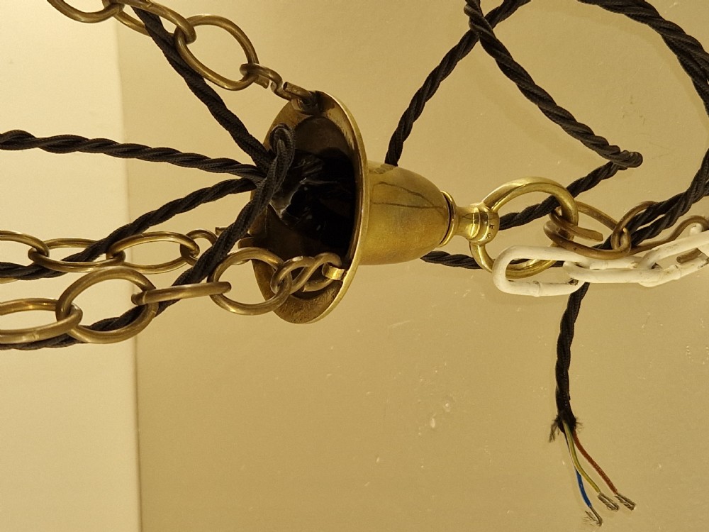 An Edwardian brass ceiling light fitting featuring three chain-suspended stiletto glass shades surrounding a central prismatic glass bowl. View III