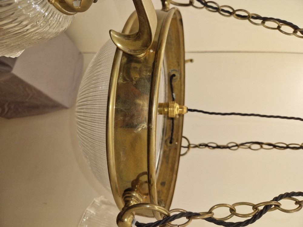 An Edwardian brass ceiling light fitting featuring three chain-suspended stiletto glass shades surrounding a central prismatic glass bowl. View IV