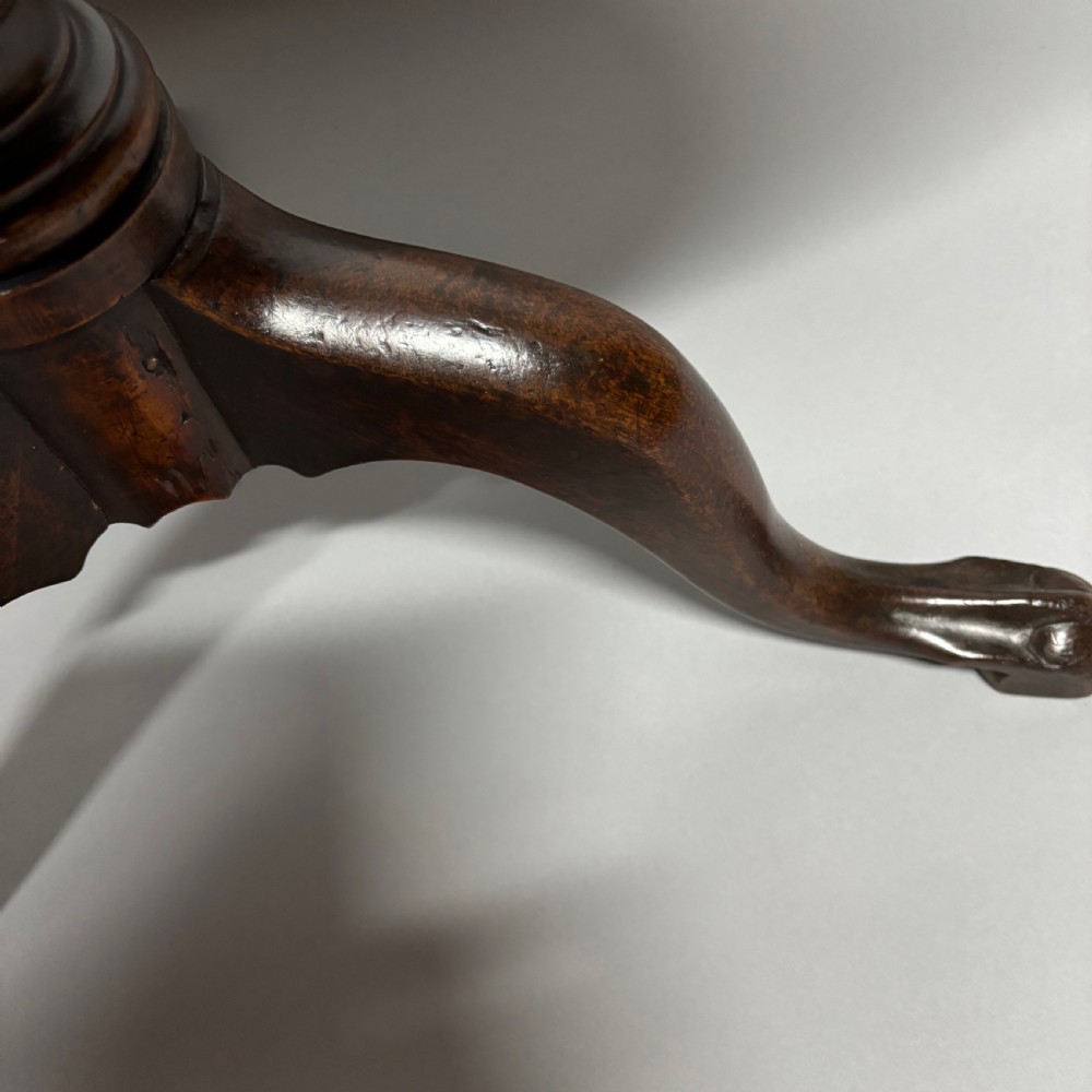 A solid circular mahogany tilt-top table shown tilted vertically on a central turned column with three cabriole legs. View VII