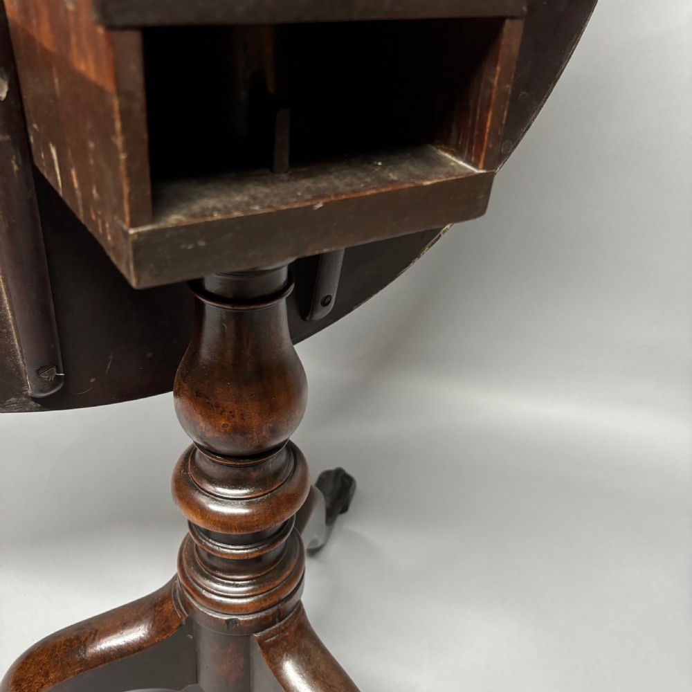 A solid circular mahogany tilt-top table shown tilted vertically on a central turned column with three cabriole legs. View VIII