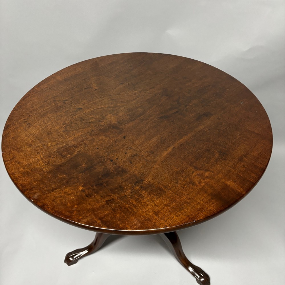 A solid circular mahogany tilt-top table shown tilted vertically on a central turned column with three cabriole legs. View XI