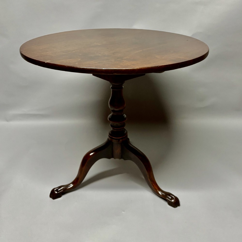 A solid circular mahogany tilt-top table shown tilted vertically on a central turned column with three cabriole legs. View XII