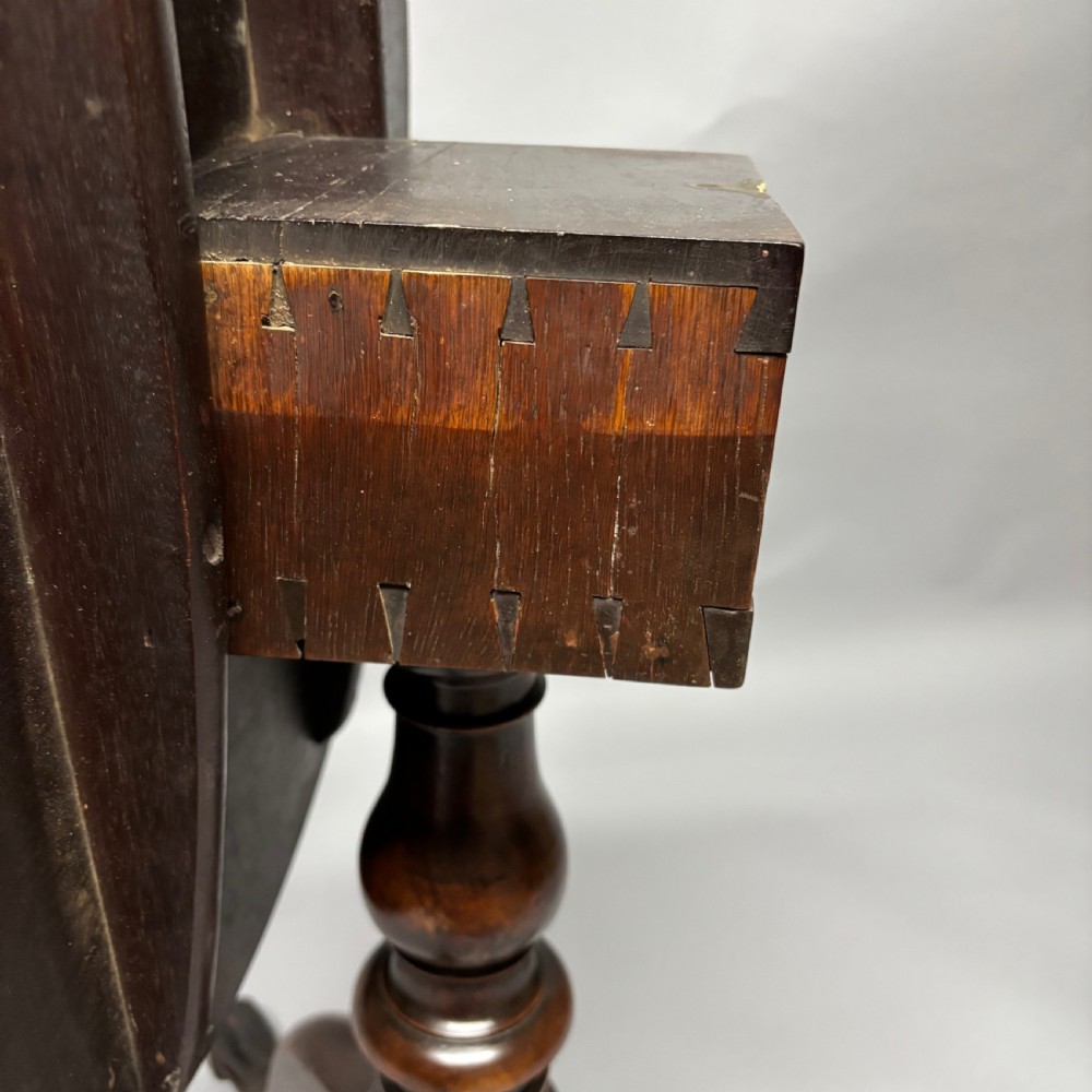 A solid circular mahogany tilt-top table shown tilted vertically on a central turned column with three cabriole legs. View XVI