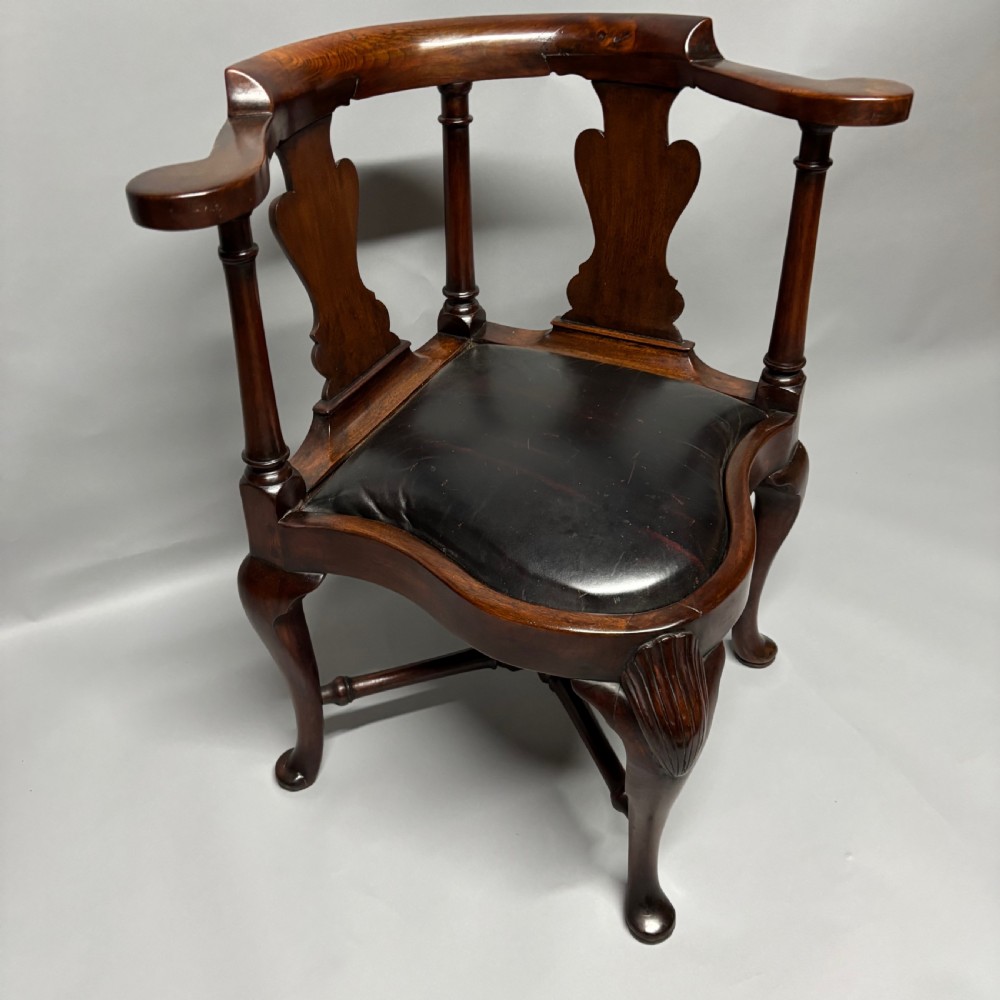An 18th-century George III dark mahogany corner chair featuring a curved top rail, twin shaped splats, a dark leather seat, turned stretchers, and a front cabriole leg carved with a shell motif. View II