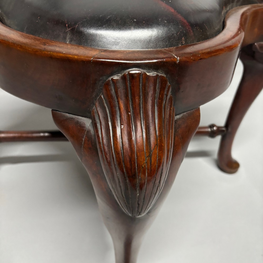An 18th-century George III dark mahogany corner chair featuring a curved top rail, twin shaped splats, a dark leather seat, turned stretchers, and a front cabriole leg carved with a shell motif. View V