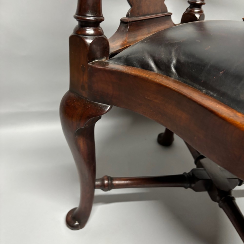An 18th-century George III dark mahogany corner chair featuring a curved top rail, twin shaped splats, a dark leather seat, turned stretchers, and a front cabriole leg carved with a shell motif. View VI