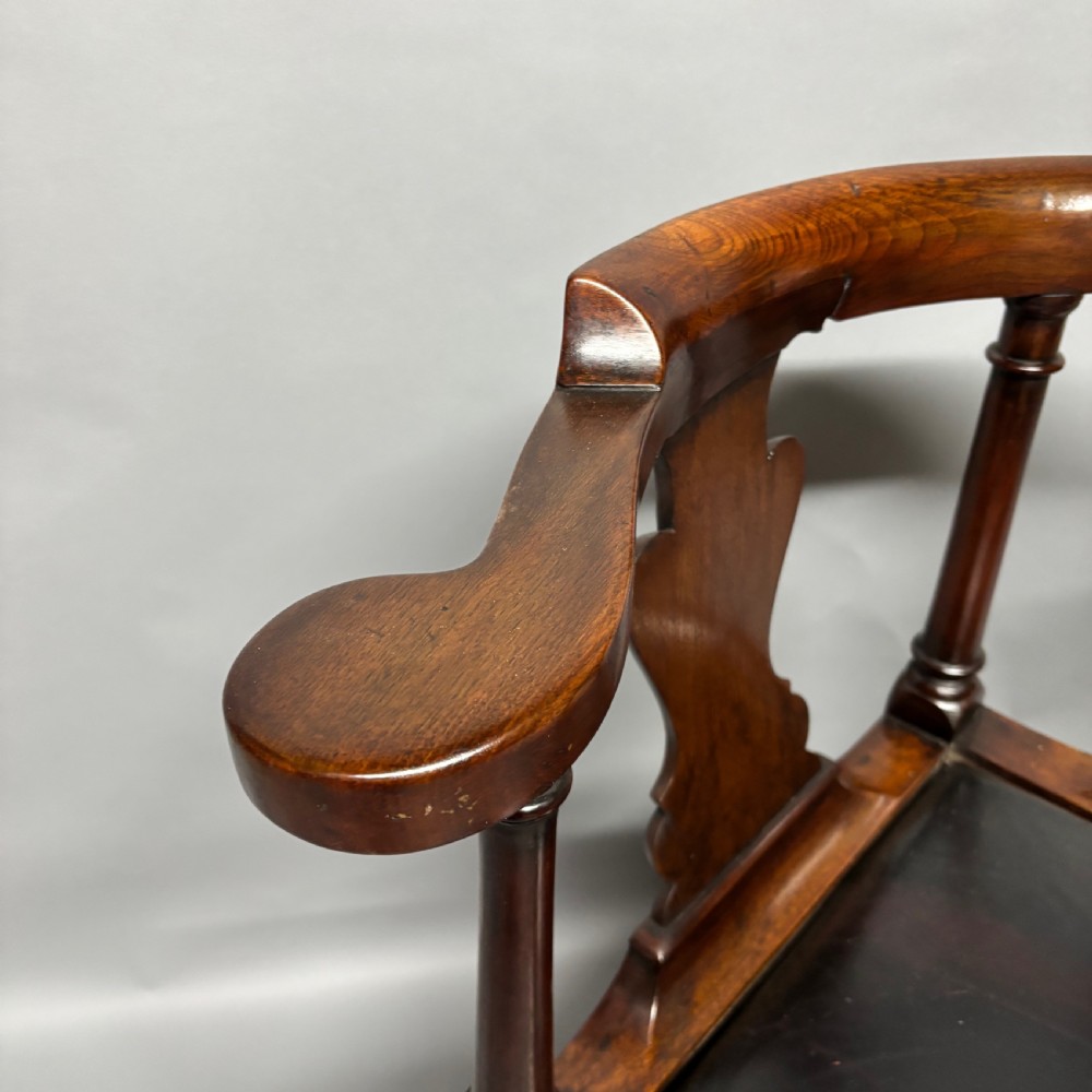 An 18th-century George III dark mahogany corner chair featuring a curved top rail, twin shaped splats, a dark leather seat, turned stretchers, and a front cabriole leg carved with a shell motif. View IX