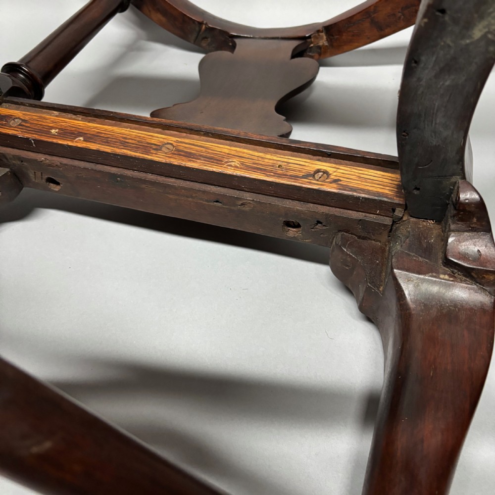 An 18th-century George III dark mahogany corner chair featuring a curved top rail, twin shaped splats, a dark leather seat, turned stretchers, and a front cabriole leg carved with a shell motif. View XV
