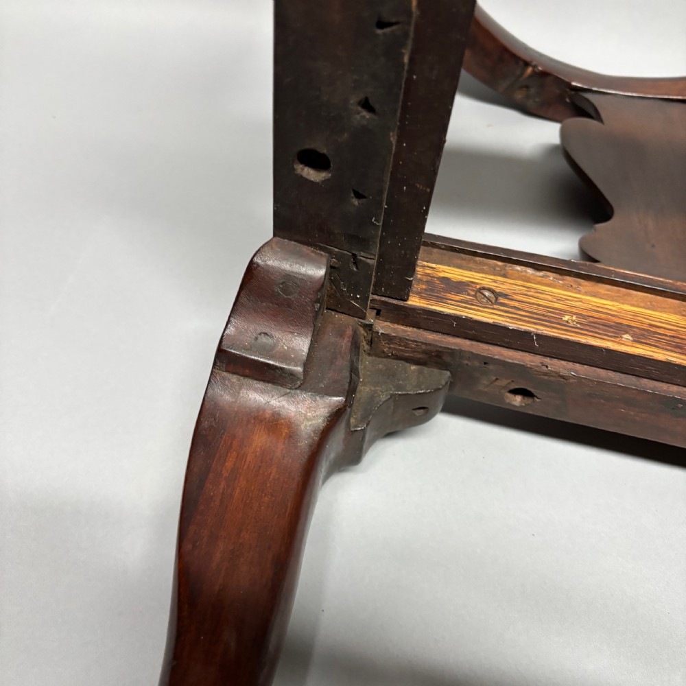 An 18th-century George III dark mahogany corner chair featuring a curved top rail, twin shaped splats, a dark leather seat, turned stretchers, and a front cabriole leg carved with a shell motif. View XVI