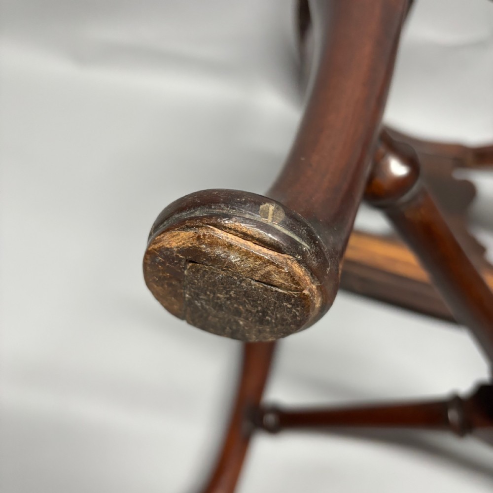 An 18th-century George III dark mahogany corner chair featuring a curved top rail, twin shaped splats, a dark leather seat, turned stretchers, and a front cabriole leg carved with a shell motif. View XVII