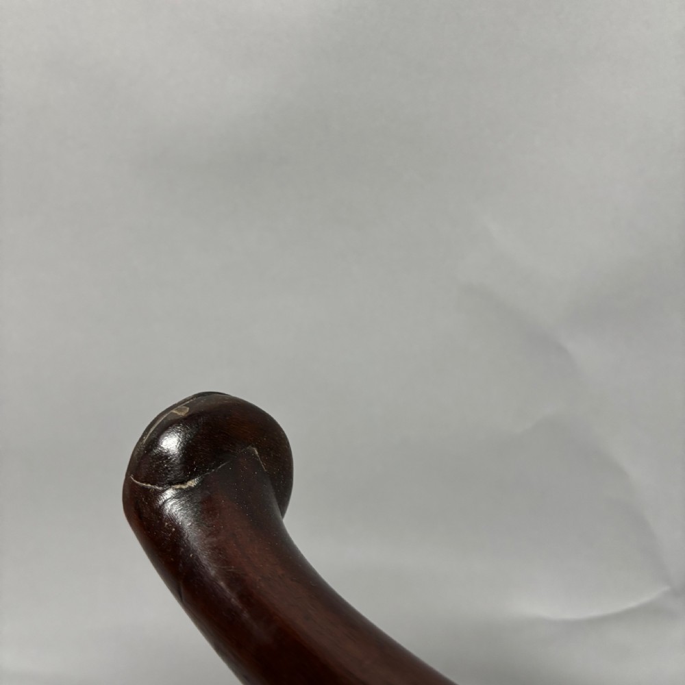 An 18th-century George III dark mahogany corner chair featuring a curved top rail, twin shaped splats, a dark leather seat, turned stretchers, and a front cabriole leg carved with a shell motif. View XVIII