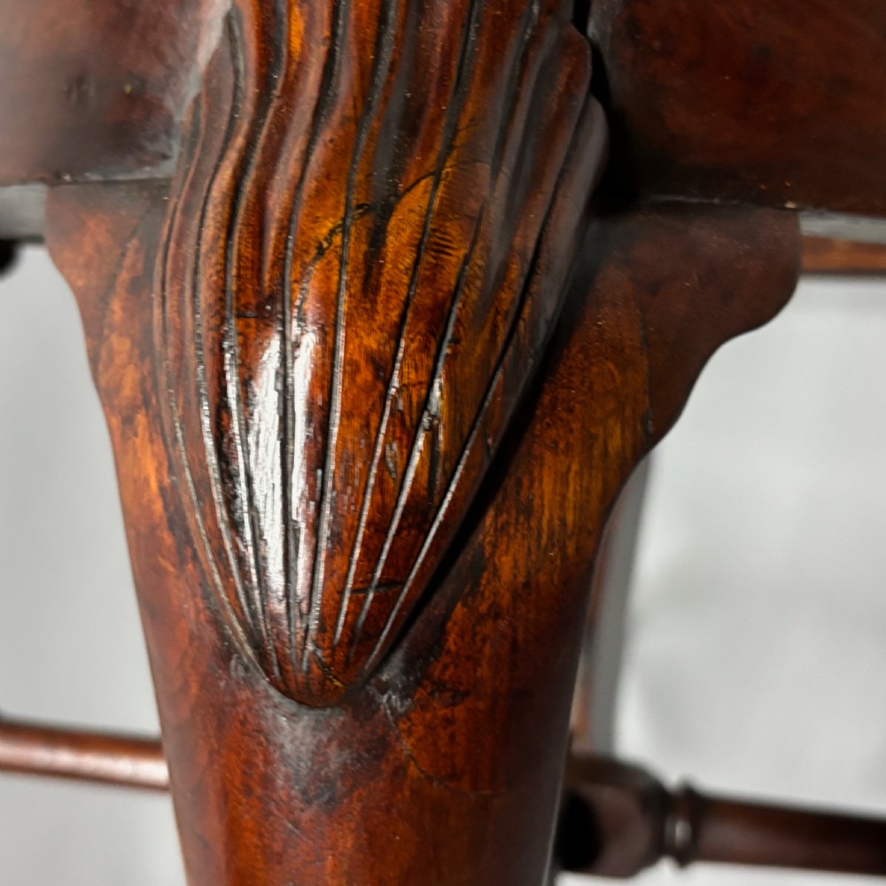 An 18th-century George III dark mahogany corner chair featuring a curved top rail, twin shaped splats, a dark leather seat, turned stretchers, and a front cabriole leg carved with a shell motif. View XXI
