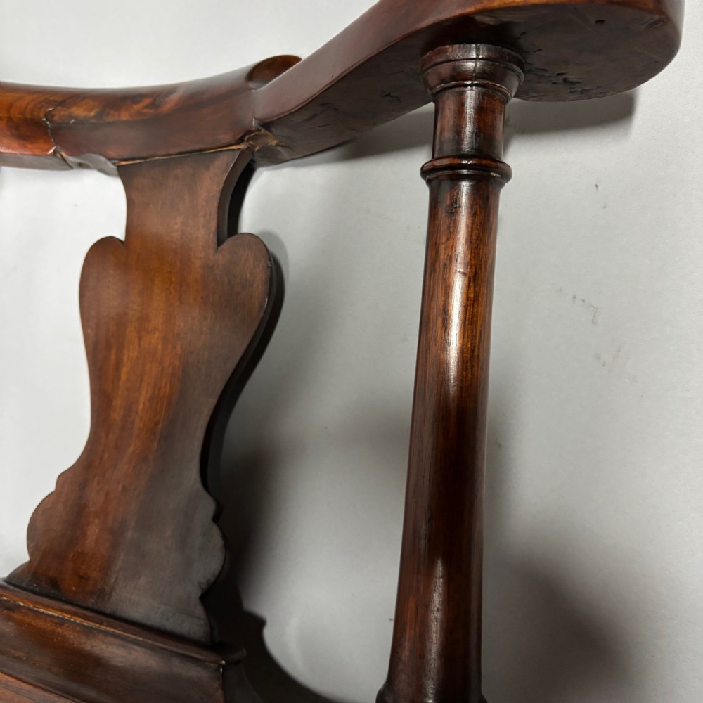 An 18th-century George III dark mahogany corner chair featuring a curved top rail, twin shaped splats, a dark leather seat, turned stretchers, and a front cabriole leg carved with a shell motif. View XXII