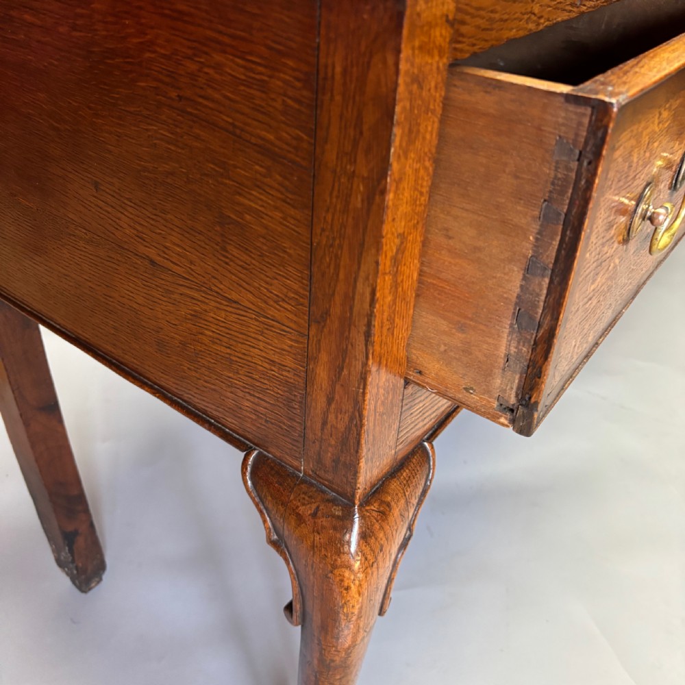 A George III period oak dresser base featuring three drawers with brass swan-neck handles and front cabriole legs. View V