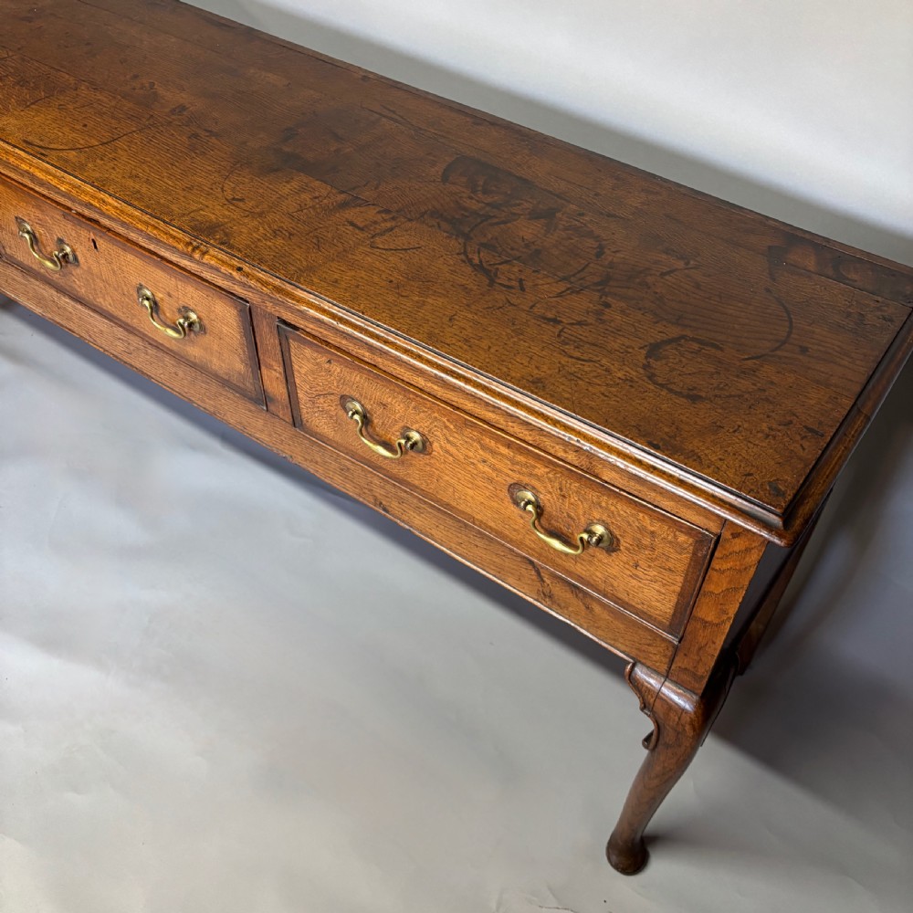 A George III period oak dresser base featuring three drawers with brass swan-neck handles and front cabriole legs. View IX