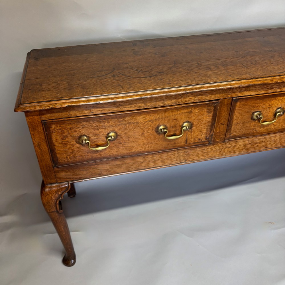 A George III period oak dresser base featuring three drawers with brass swan-neck handles and front cabriole legs. View XI