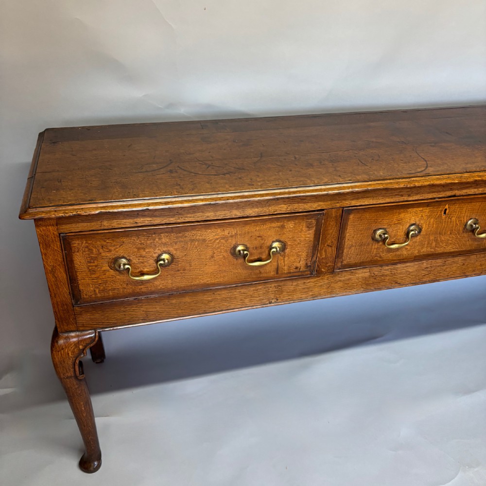 A George III period oak dresser base featuring three drawers with brass swan-neck handles and front cabriole legs. View XII