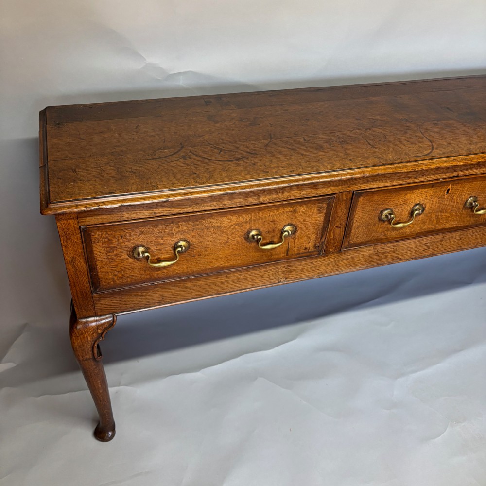 A George III period oak dresser base featuring three drawers with brass swan-neck handles and front cabriole legs. View XXII