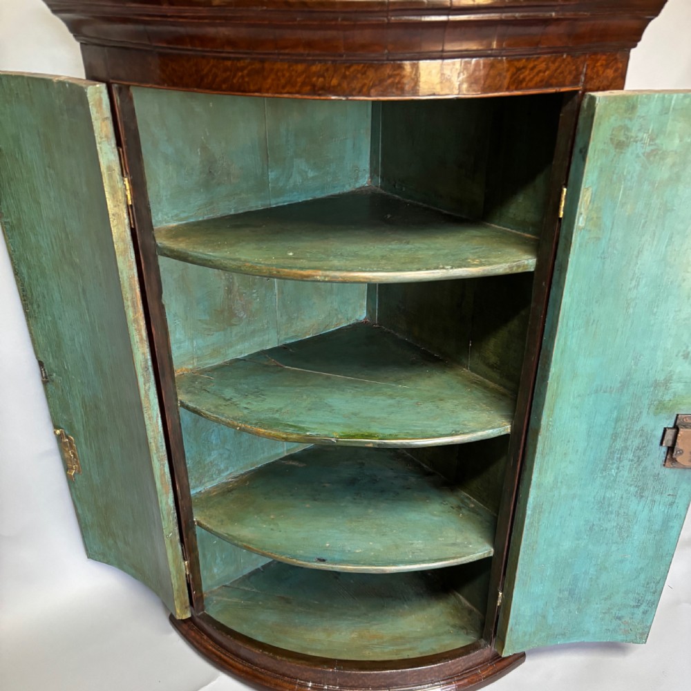 A Georgian bowfront mahogany corner cupboard featuring distinctive plum pudding grain, brass escutcheons, and visible brass H-hinges. View XI