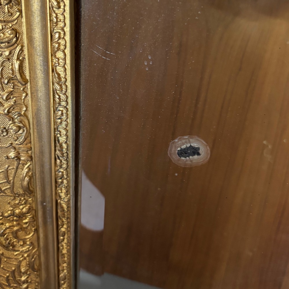A 19th-century French giltwood wall mirror featuring an intricate floral cresting, molded frame, and carved scroll corner accents. View VIII