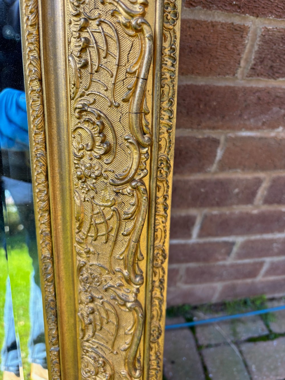 A 19th-century French giltwood wall mirror featuring an intricate floral cresting, molded frame, and carved scroll corner accents. View XI