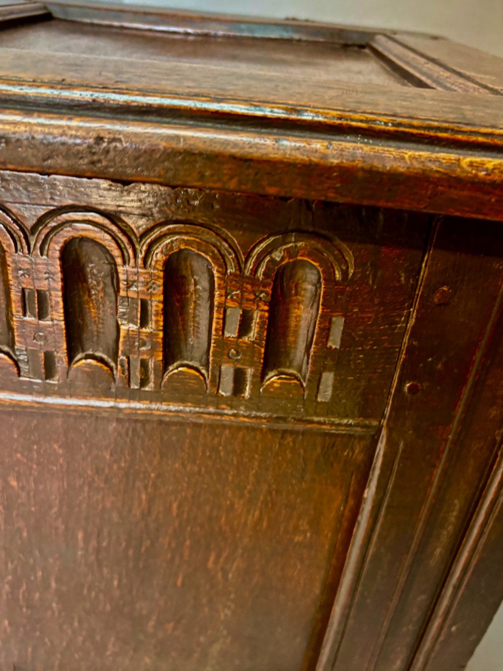 An eighteenth-century dark oak coffer with an arcaded carved top frieze, three lower plain panels, and a panelled hinged top. View III