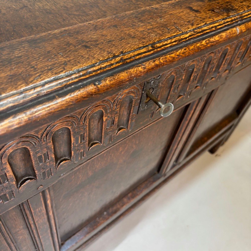 An eighteenth-century dark oak coffer with an arcaded carved top frieze, three lower plain panels, and a panelled hinged top. View IV