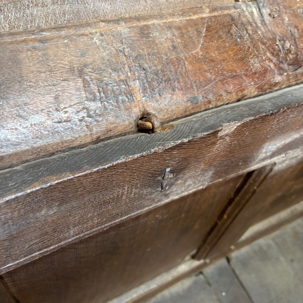 An eighteenth-century dark oak coffer with an arcaded carved top frieze, three lower plain panels, and a panelled hinged top. View V