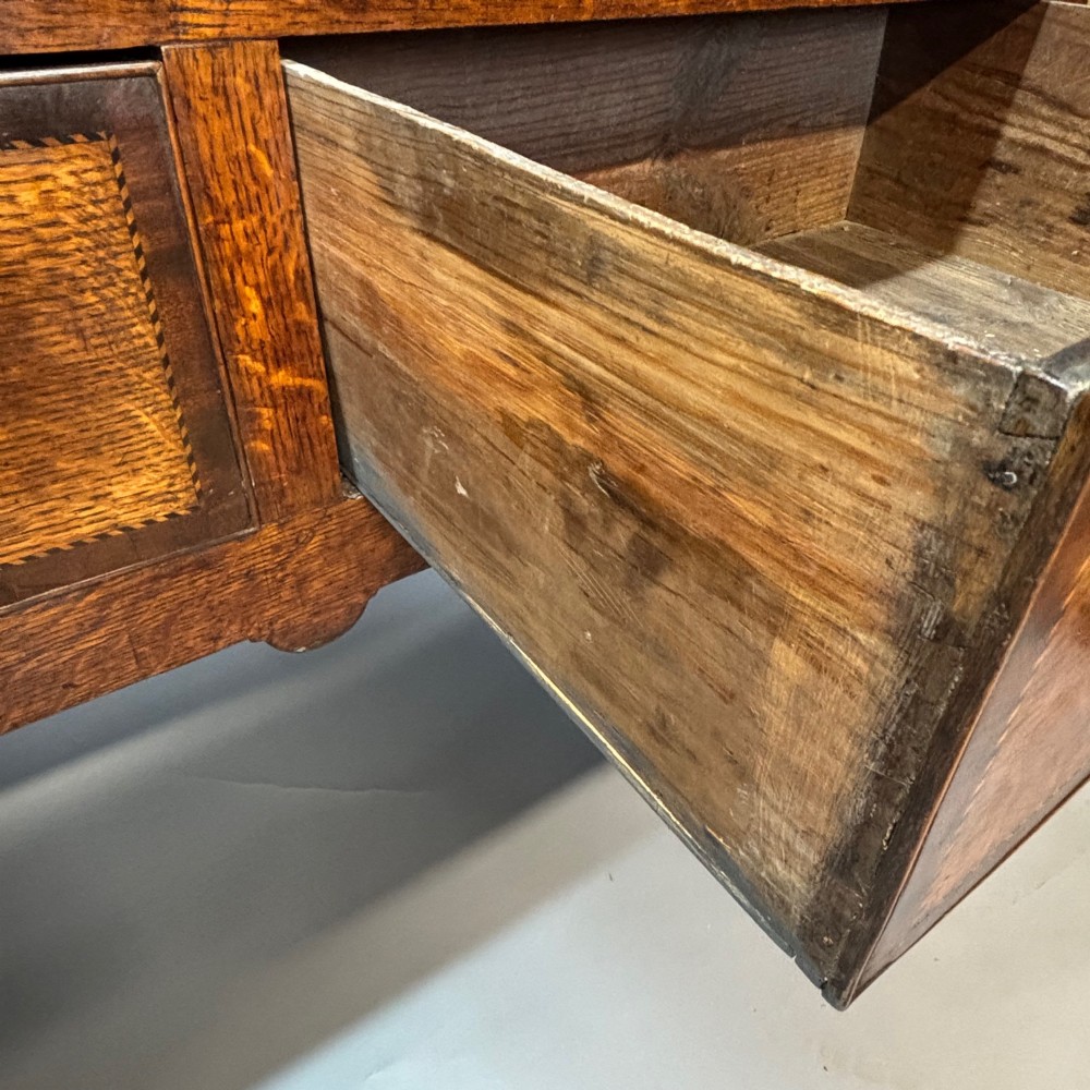 An eighteenth-century oak low dresser featuring three crossbanded drawers with brass swan-neck handles, elevated on four cabriole legs. View VII