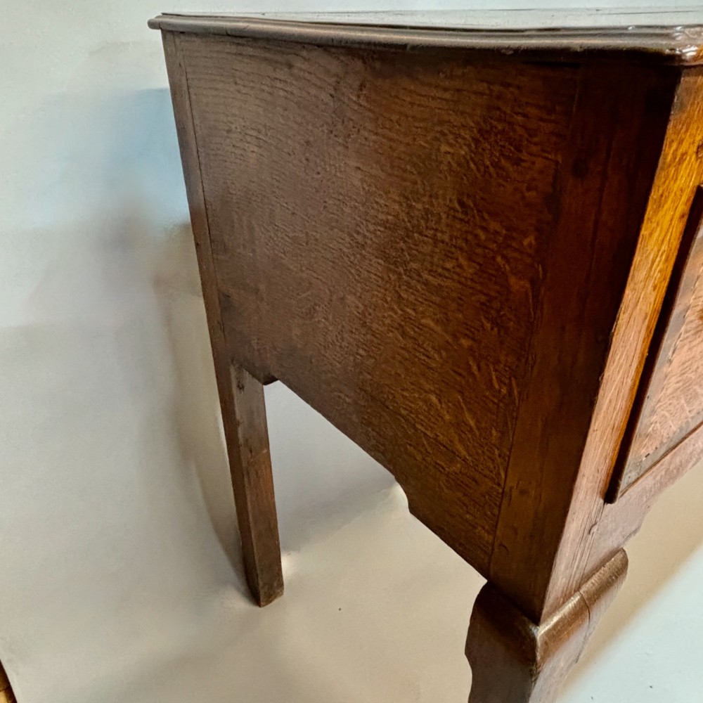 An eighteenth-century oak low dresser featuring three crossbanded drawers with brass swan-neck handles, elevated on four cabriole legs. View XIII