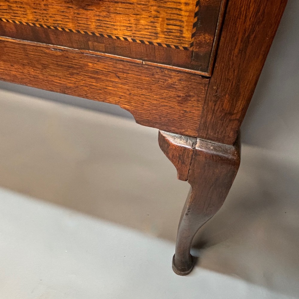 An eighteenth-century oak low dresser featuring three crossbanded drawers with brass swan-neck handles, elevated on four cabriole legs. View XIV