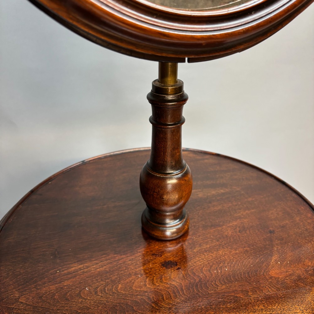 A Victorian dark mahogany shaving stand featuring an adjustable circular mirror, a round tier, a hinged compartment, turned support stem, and tripod cabriole legs. View IV