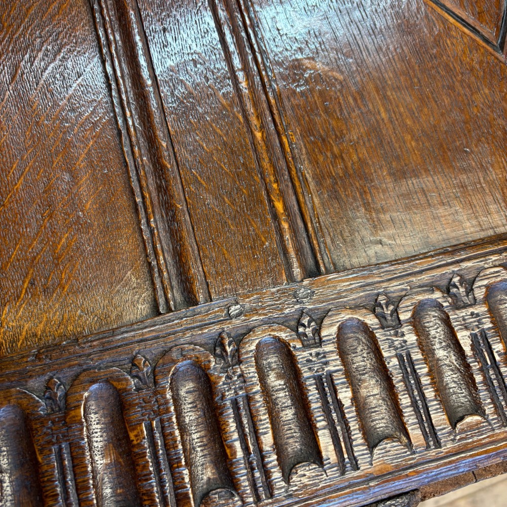 A seventeenth-century dark oak coffer featuring four carved panelled sections with diamond lozenges and decorative carved borders. View VI