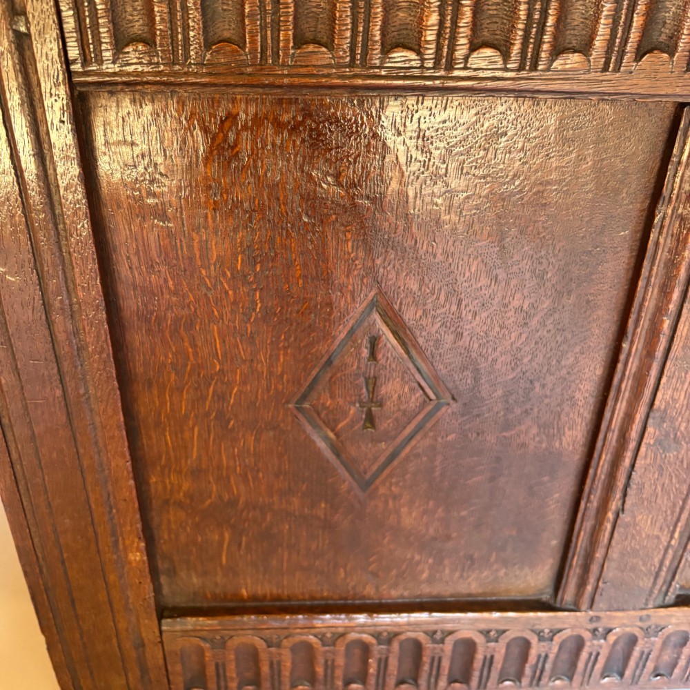 A seventeenth-century dark oak coffer featuring four carved panelled sections with diamond lozenges and decorative carved borders. View VII