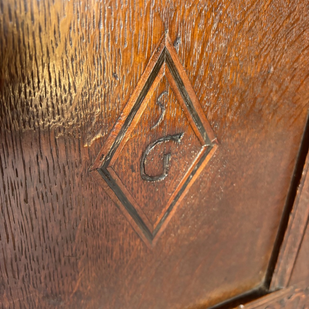 A seventeenth-century dark oak coffer featuring four carved panelled sections with diamond lozenges and decorative carved borders. View VIII