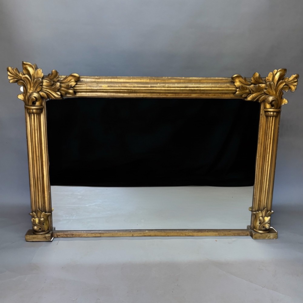 A nineteenth-century rectangular giltwood mirror featuring fluted side columns topped with carved acanthus leaf capitals.