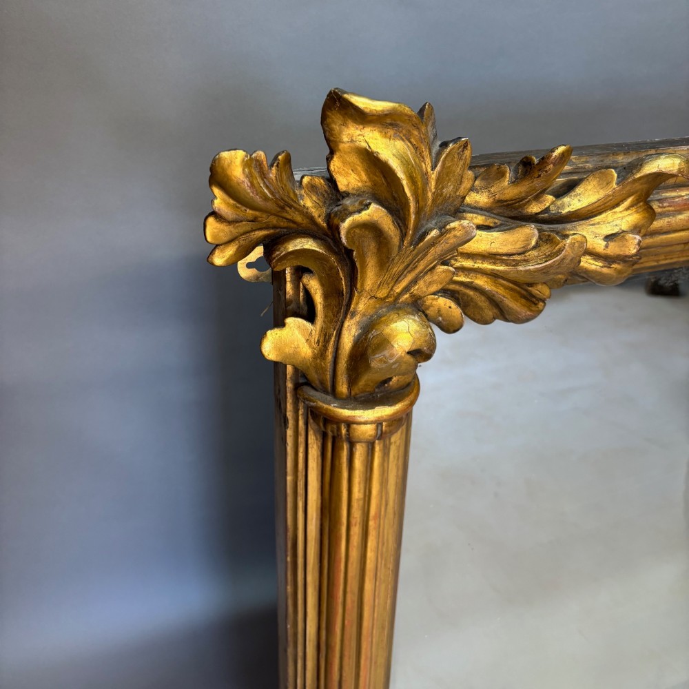 A nineteenth-century rectangular giltwood mirror featuring fluted side columns topped with carved acanthus leaf capitals. View II