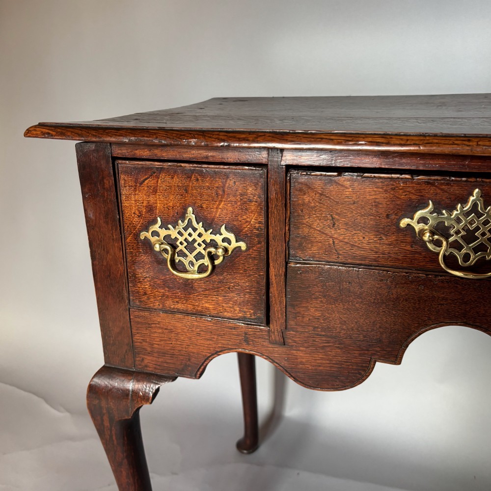 An 18th-century George II oak lowboy featuring three drawers with pierced brass handles, a shaped apron, and four cabriole legs with pad feet. View III