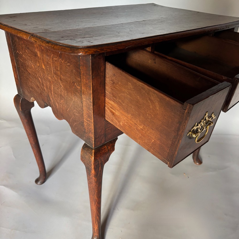 An 18th-century George II oak lowboy featuring three drawers with pierced brass handles, a shaped apron, and four cabriole legs with pad feet. View IV