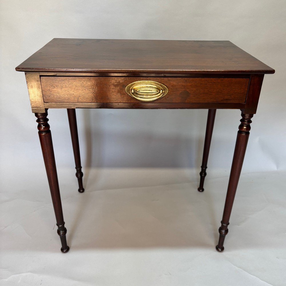 A George III mahogany side table featuring a single drawer with an oval brass handle and slender turned legs. View III